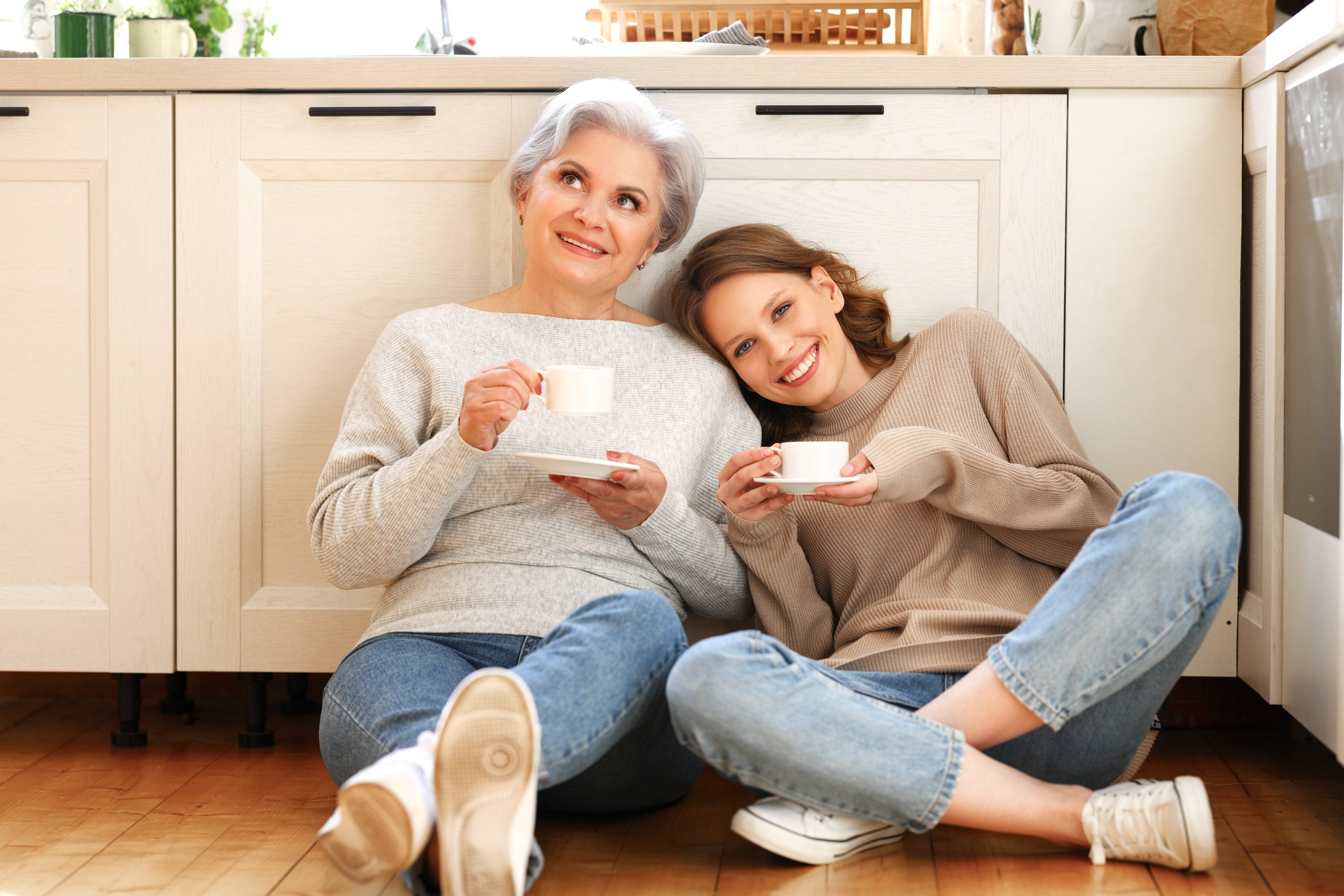 Mother and daughter drinking coffee and talking in kitchen