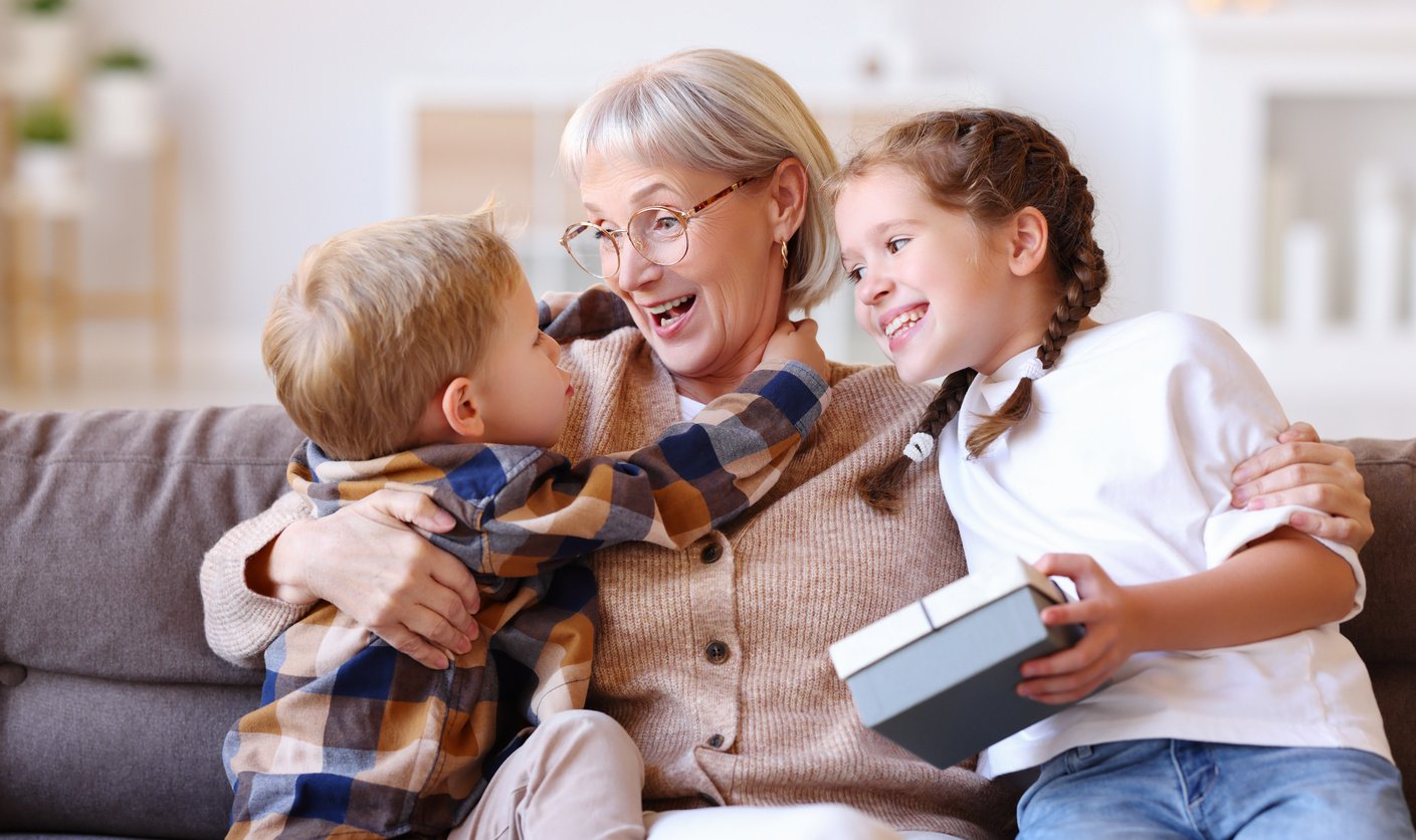 Excited grandmother hugging grandchildren with gift